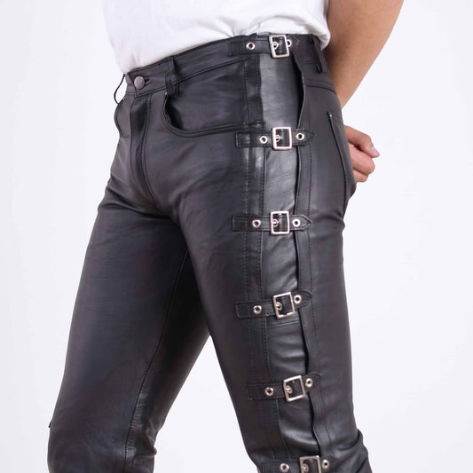 Close up side view of high waisted black leather pants showing silver roller buckle straps along the hip and thigh