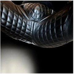 Black quilted leather jacket sleeve with diamond stitching, shown close-up against a dark background.