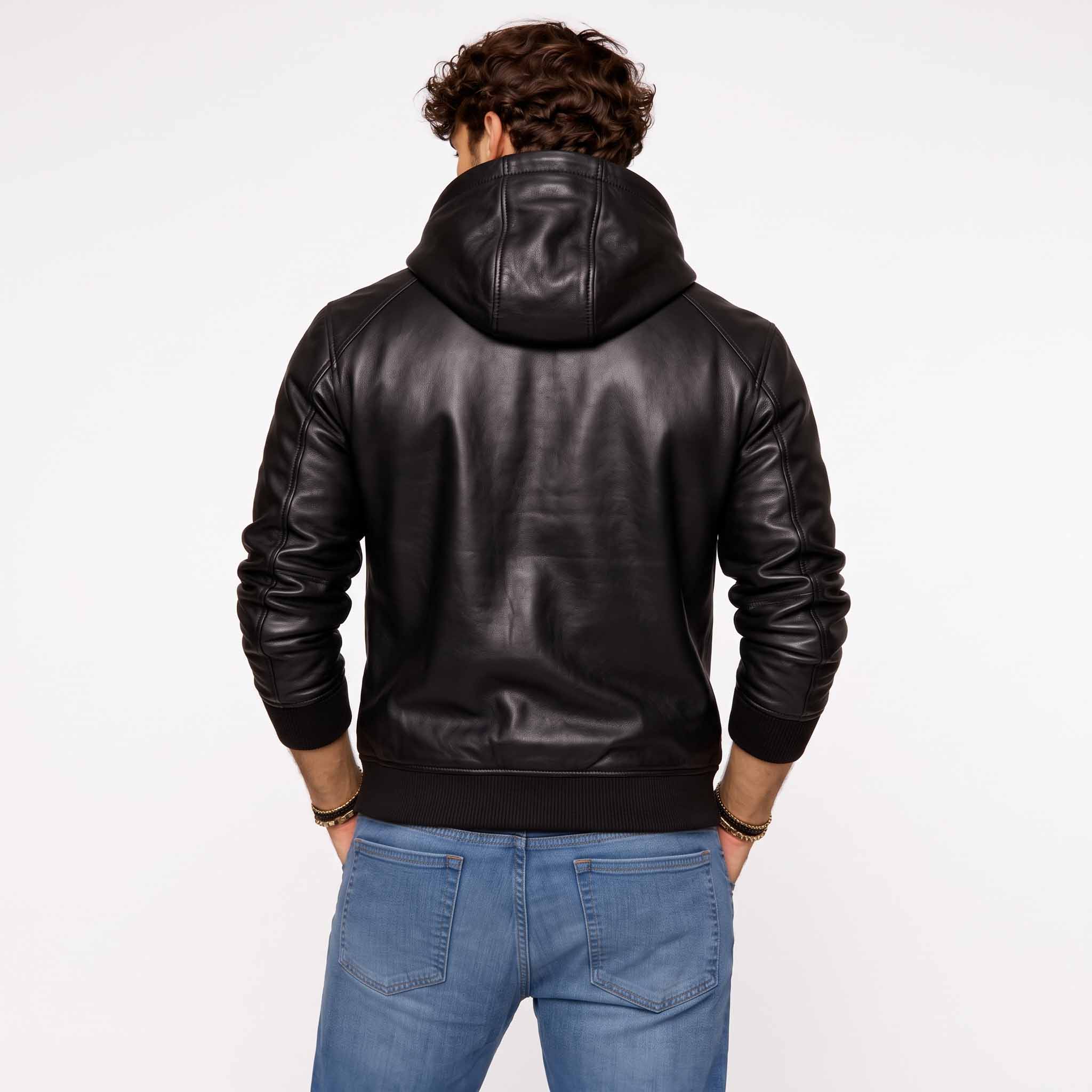 Back view of man wearing tailored black leather hoodie showing clean back yoke, hood drape, and ribbed waistband over blue jeans