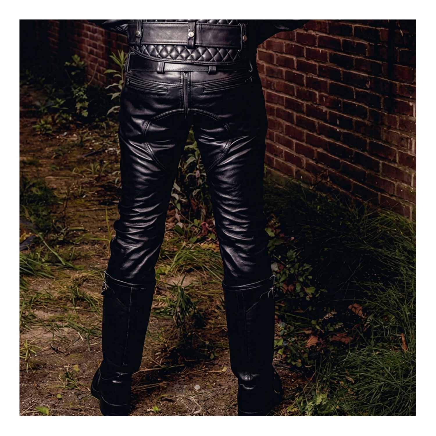 Back view showing the saddle back seam paneling, rear YKK zipper, and tailored seat fit of men's black leather riding pants.