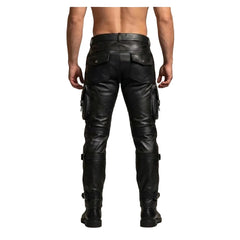 Rear view of a man wearing dark green and black leather cargo pants with utility pockets and straps, paired with black boots against a neutral studio background.