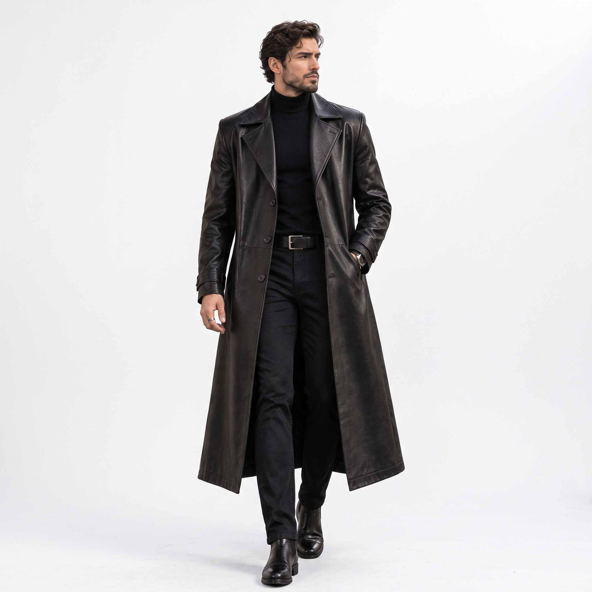 Full length front view of handsome man walking in handmade black genuine leather long trench coat open over dark turtleneck and trousers