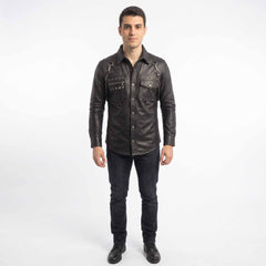 Full length studio shot of man wearing handmade black studded leather shirt paired with dark slim jeans and black leather boots