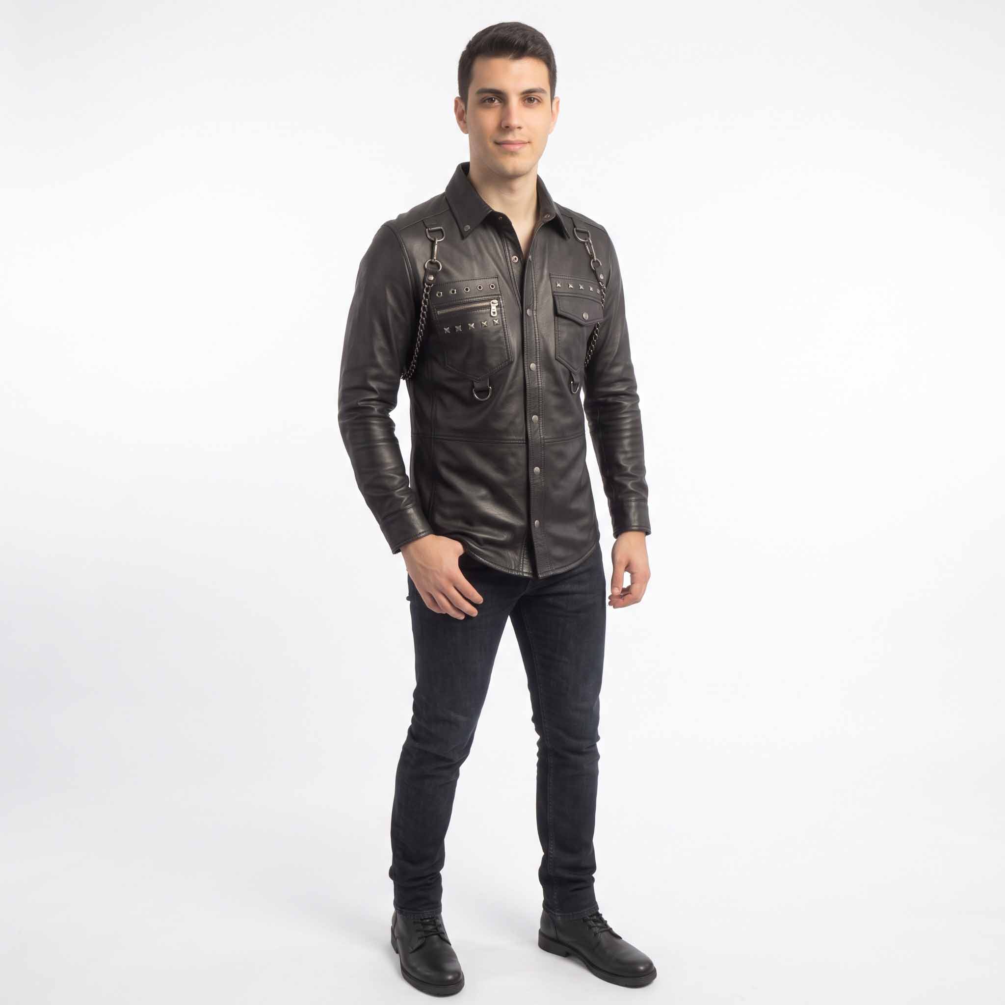 Full body perspective of model in black leather punk rock overshirt and denim jeans posing against seamless white background