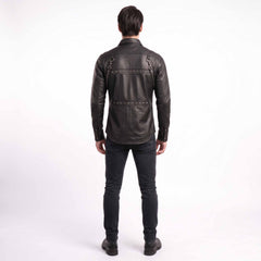 Full length rear studio view of man wearing tailored black leather studded shirt showing curved lower hemline and studded back yoke