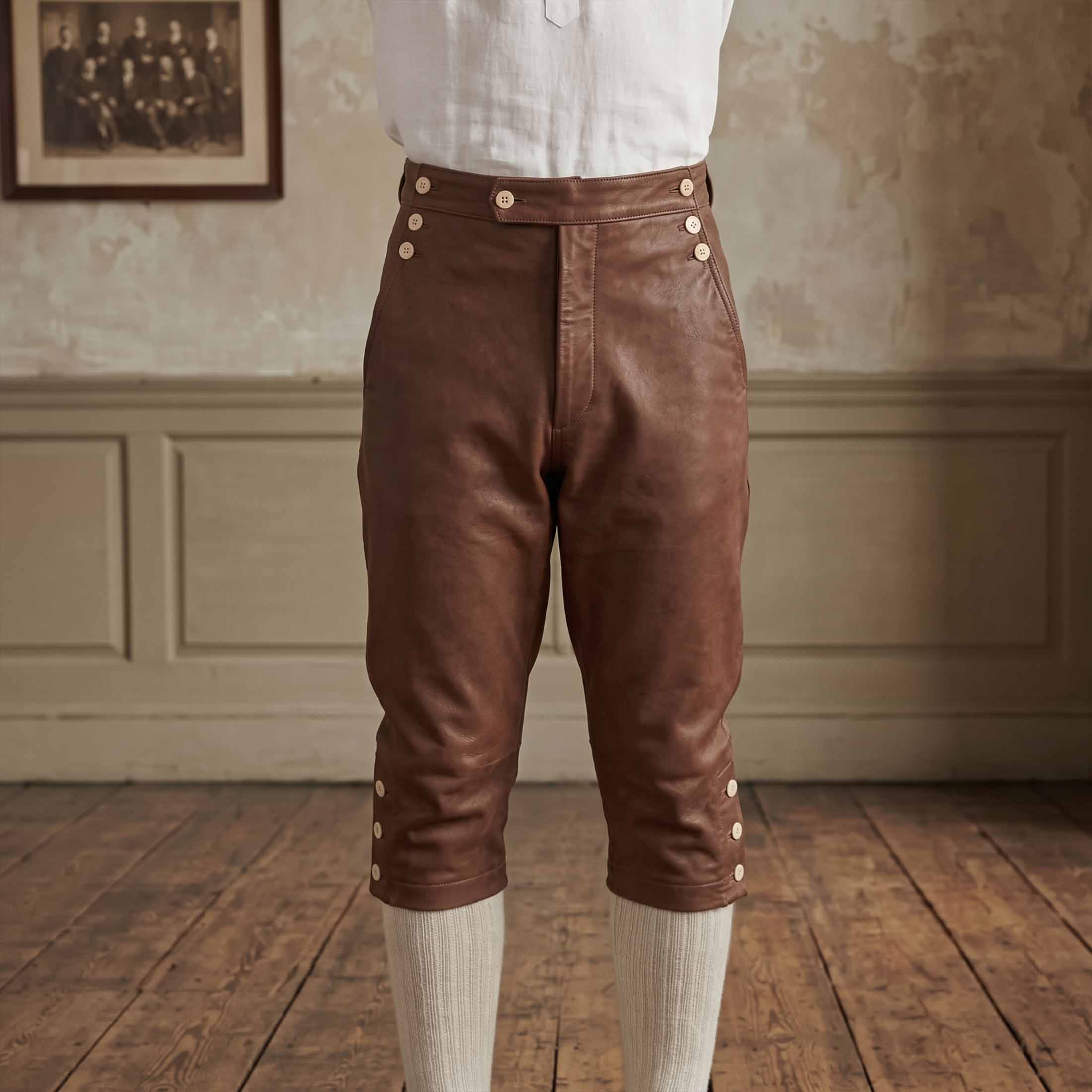 Front view of brown leather colonial knickers highlighting button-up drop fall flap and triple-button knee closures over white stockings