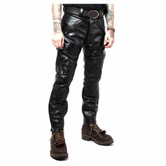 Front view of men's black leather biker jeans displaying angled brass zipper pockets, belt loops, and diamond-quilted knee panels.