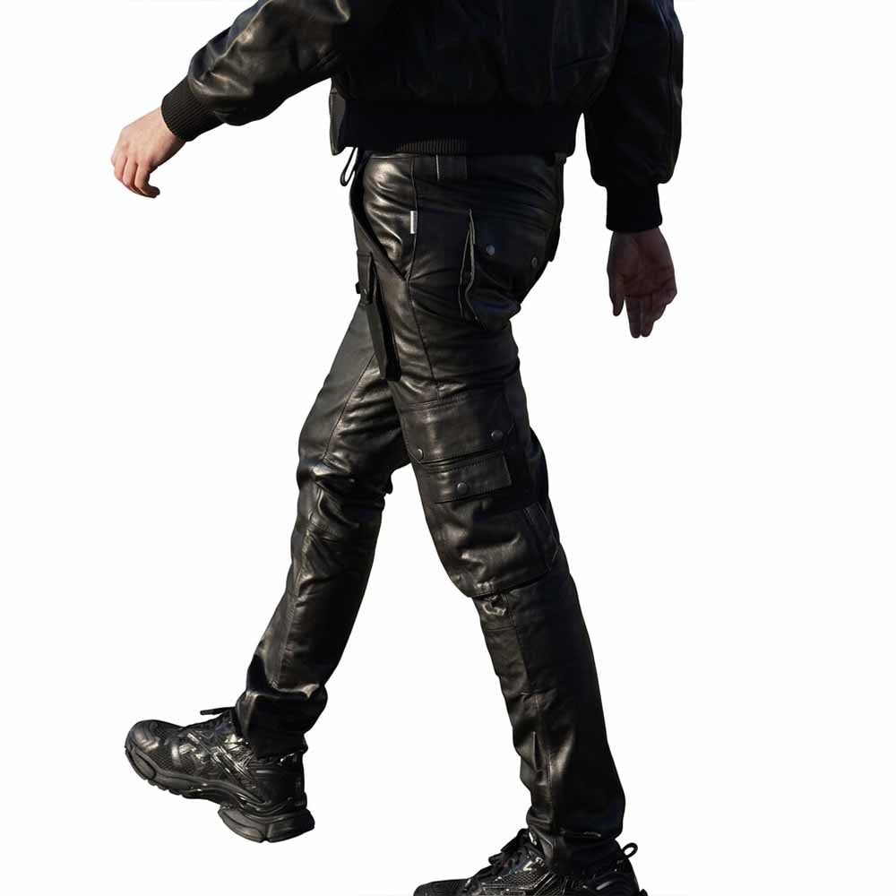 Side profile view of a man walking wearing black full-grain leather biker cargo trousers paired with sneakers.