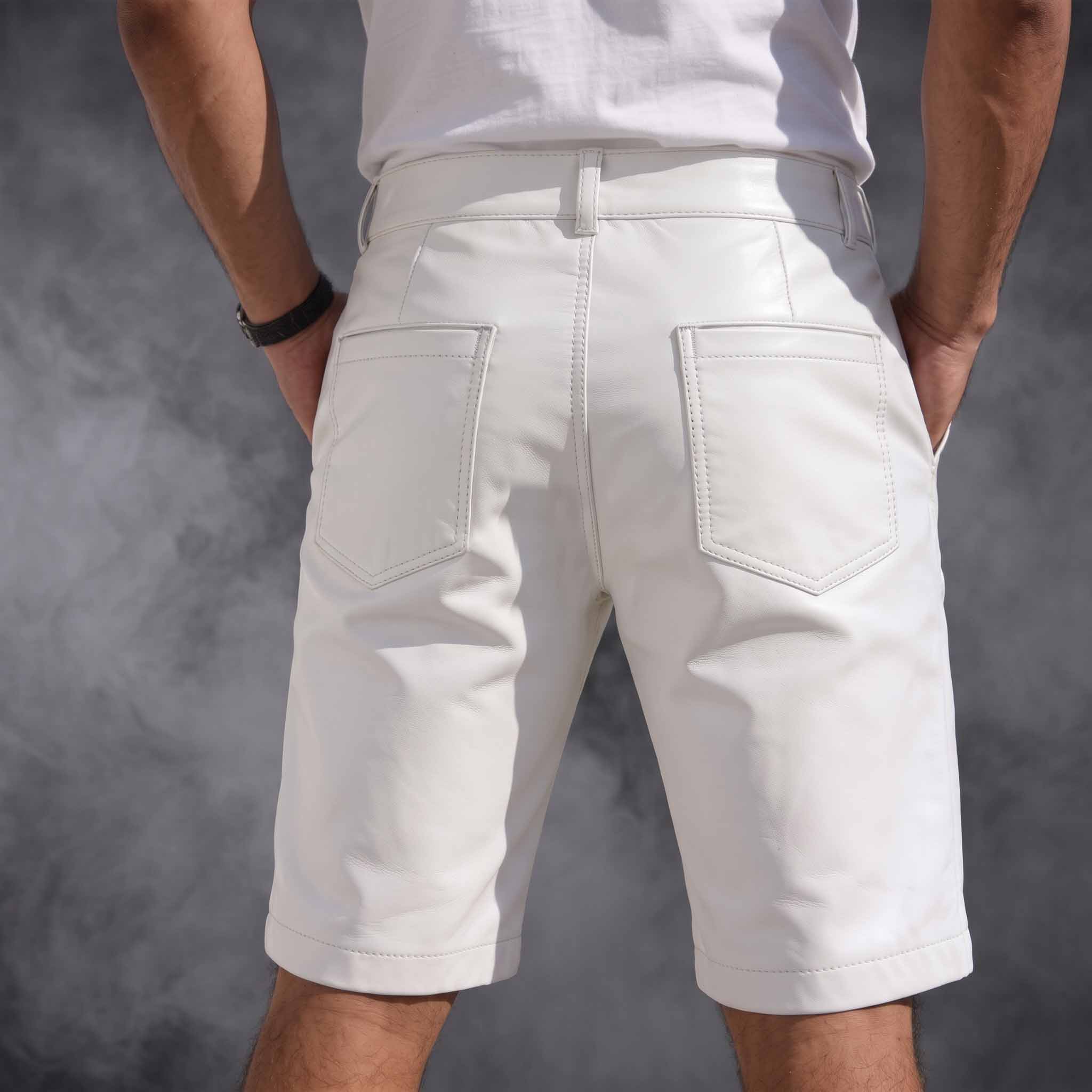 Direct rear view of male model in tailored white leather cargo shorts showing rear patch pockets, belt loops, and contoured back yoke