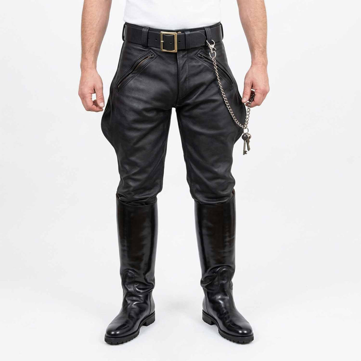 Front view of men wearing black real cowhide leather breeches with front zip pockets, belt, key chain, and tall black leather boots against a white background.