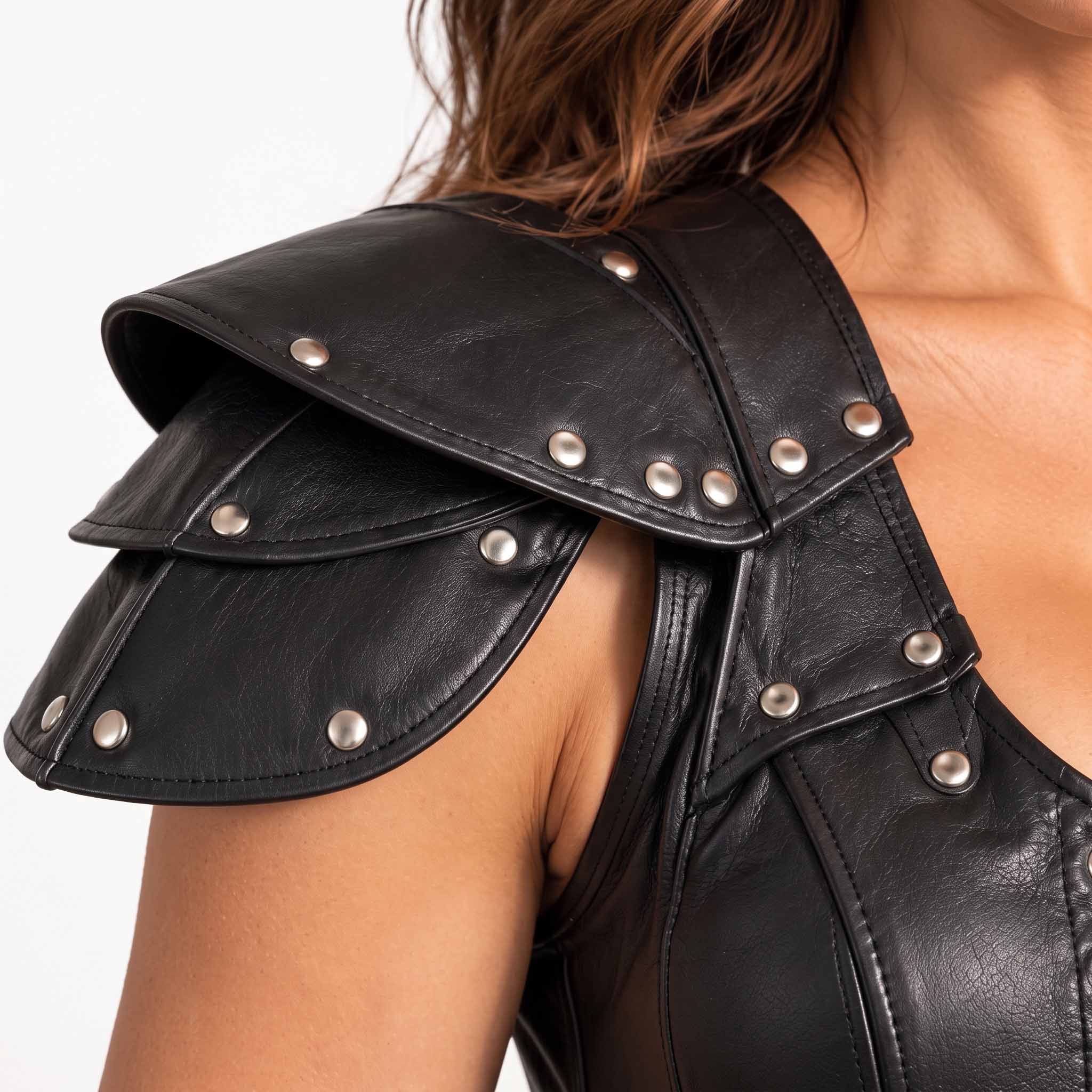 Close up view of tiered black leather shoulder pauldron armor plates detailed with silver metal dome studs and reinforced perimeter stitching
