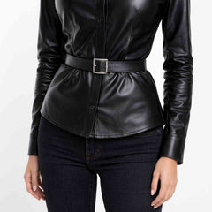 Close up view of the rectangular metal belt buckle and gathering details on a black real leather peplum shirt.