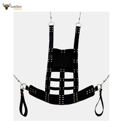 A black leather web sex swing sling with stirrups and a soft leather cushion. The sling is in a trapezoid shape, featuring a series of rivets for attachment and suspension straps for chain or rope play.