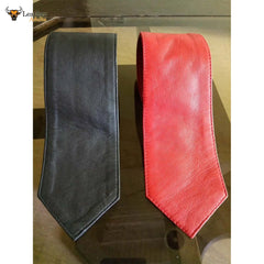 Two men's ties, one in black and the other in red, made of genuine sheepskin leather, displayed on a glass surface.